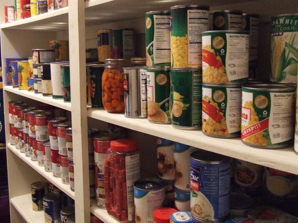 Cans, jars, and packages of food on pantry shelves.
